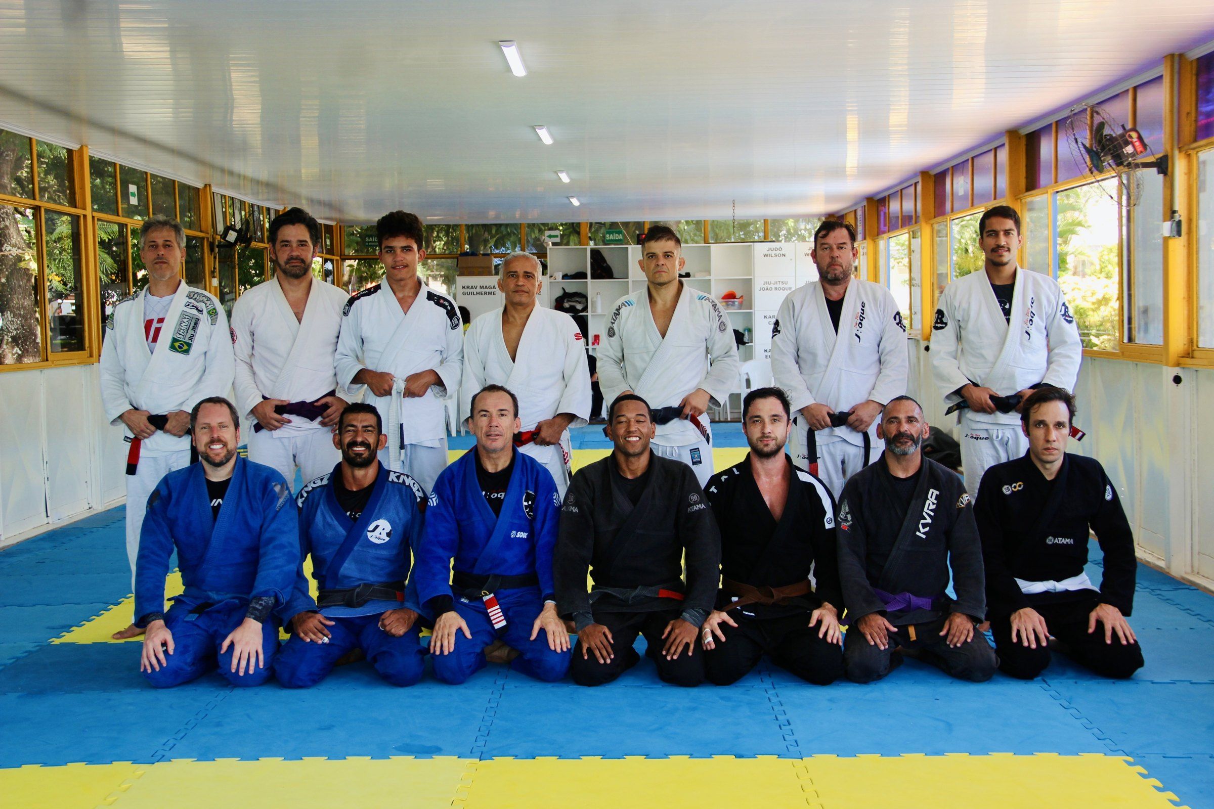 Equipe JRoque reunida no tatame, faixas pretas de quimono azul, branco e preto